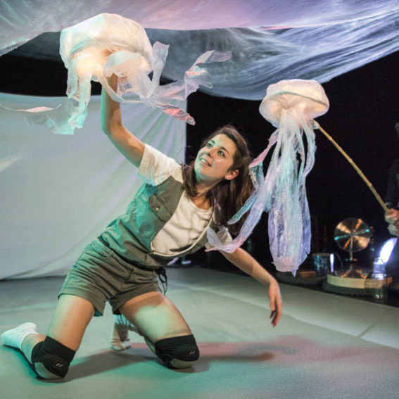 Foto: Moon Saris Beeld uit jeugdvoorstelling Vaarwel, vrouw op podium met kwallenpoppen